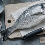 Écailleur manuel inox écaillant un poisson, écailles décollées sans abîmer la chair